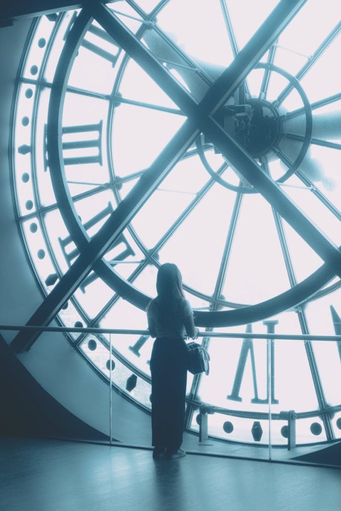 A woman stands looking out from the clock window at Musée d'Orsay, Paris.